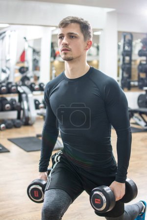 Photo for Fit handsome young man workout with weights in the gym. - Royalty Free Image