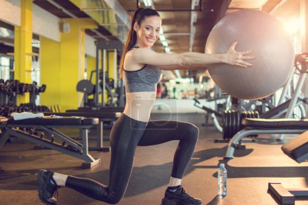 Téléchargez les photos : Attrayant jeune femme en vêtements de sport de travail avec balle de remise en forme dans la salle de gym. - en image libre de droit
