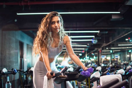 Photo for Beautiful young woman exercising on cycling machine in the gym. - Royalty Free Image