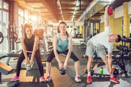 Photo for Group of three young athletes doing kettlebell exercise during a crossfit workout at the gym - Royalty Free Image