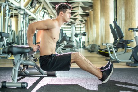 Photo for Handsome young shirtless guy doing bench dips exercises at gym - Royalty Free Image