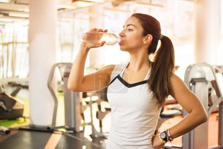 Téléchargez les photos : Fille sportive boire de l'eau dans une salle de gym. - en image libre de droit