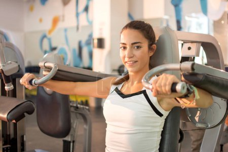 Foto de Mujer joven haciendo ejercicio en la máquina en el gimnasio. - Imagen libre de derechos