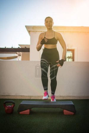 Photo for Sporty young woman exercising on fitness stepper outdoors. - Royalty Free Image