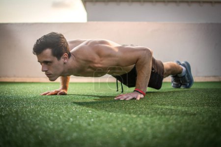 Photo for Muscular man doing push ups outdoors. - Royalty Free Image
