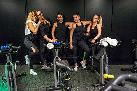 Téléchargez les photos : Groupe de jeunes femmes en vêtements de sport posant dans la salle de gym. - en image libre de droit