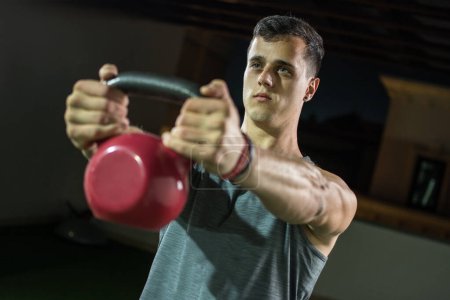 Foto de Retrato del hombre musculoso guapo haciendo ejercicio con la campana de la tetera en el gimnasio. - Imagen libre de derechos