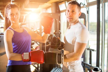 Photo for Young couple posing with red boxing gloves at the gym. - Royalty Free Image