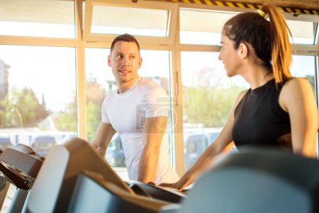 Photo for Sporty friends walking on treadmill and talking at gym - Royalty Free Image