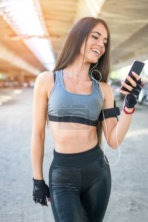 Photo for Happy sporty girl listening to music on mobile phone outdoors - Royalty Free Image