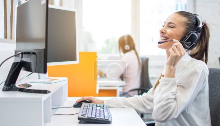 Téléchargez les photos : Heureuse femme souriante opérateur de service à la clientèle travaillant sur ordinateur dans le bureau. - en image libre de droit