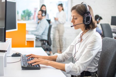 Photo for Attractive helpline worker woman using computer in call center office. - Royalty Free Image