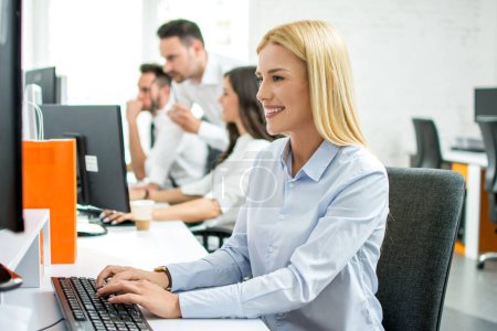 Téléchargez les photos : Jeune femme d'affaires travaillant sur ordinateur à son bureau au bureau - en image libre de droit