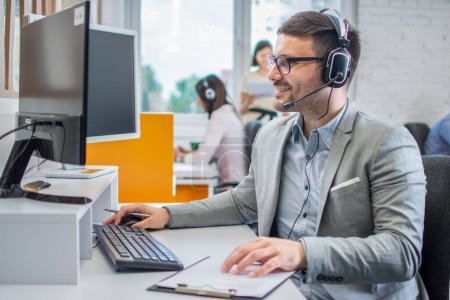 Foto de Ejecutivo de servicio al cliente sonriente con auriculares trabajando en el centro de llamadas. - Imagen libre de derechos
