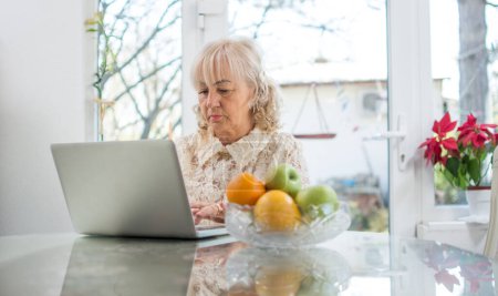 Foto de Retrato de una hermosa mujer mayor que trabaja en el ordenador portátil en el interior - Imagen libre de derechos