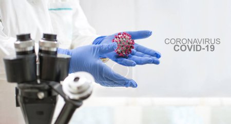 Téléchargez les photos : Les scientifiques mains dans des gants de protection tenant Corona VIrus. Virus Corona Covid-19 Texte - en image libre de droit