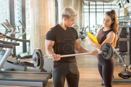 Photo for Young handsome man exercising under control of professional female coach in gym - Royalty Free Image