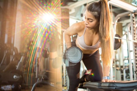 Photo for Attractive sporty woman lifting dumbbell at gym - Royalty Free Image