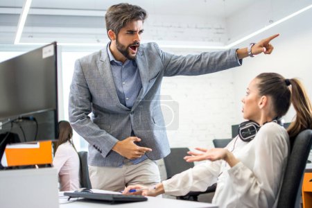 Photo for Angry boss firing upset female employee in office. Young male business manager yelling at scared and stressed business woman at her workplace. - Royalty Free Image