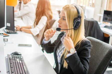 Téléchargez les photos : Opérateur de soutien technique attrayant femme en costume et casque de travail sur ordinateur dans le centre d'appel - en image libre de droit
