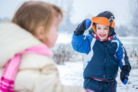 Téléchargez les photos : Frère et sœur jouant dans un paysage hivernal enneigé - en image libre de droit