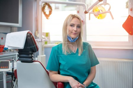 Portrait d'une jeune dentiste blonde assise sur son lieu de travail dans un cabinet dentaire