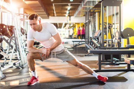 Photo for Young athletic man stretching in gym - Royalty Free Image