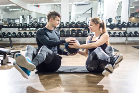 Téléchargez les photos : Couple sportif faisant de l'exercice abdominal avec des balles de fitness à la salle de gym. - en image libre de droit