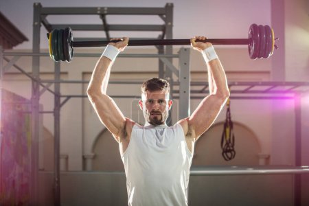 Foto de Hombre guapo fuerte levantando pesas en el gimnasio al aire libre. - Imagen libre de derechos
