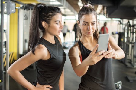 Photo for Two female friends taking a selfie photo at gym. - Royalty Free Image