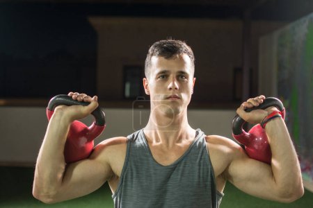 Foto de Retrato del joven musculoso levantando pesas en el gimnasio. - Imagen libre de derechos