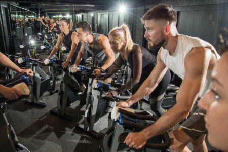 Téléchargez les photos : Musclé jeunes hommes et femmes en cours de cyclisme à la salle de gym. - en image libre de droit