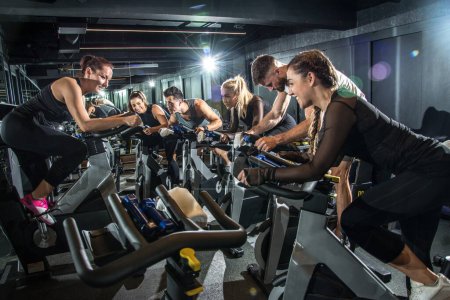 Photo for Group of sporty people with their coach training on cycling class in gym. - Royalty Free Image