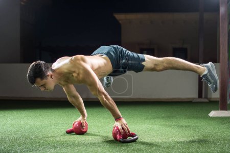 Foto de Joven musculoso haciendo handstand y equilibrando en kettlebells en el gimnasio. - Imagen libre de derechos
