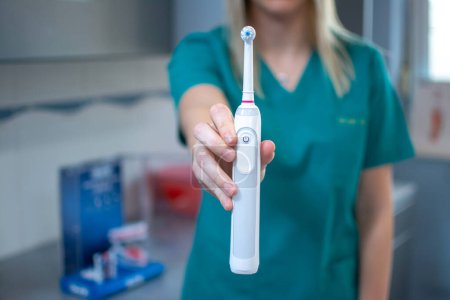 Zahnärztinnen halten in Zahnarztpraxis elektrische Zahnbürste in der Hand