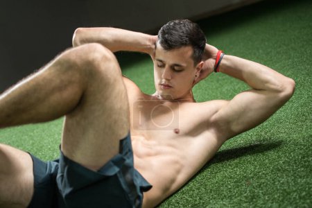 Photo for Young handsome shirtless man doing sit ups in the gym. - Royalty Free Image