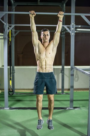 Foto de Hombre musculoso haciendo entrenamiento de fuerza en barra horizontal al aire libre. - Imagen libre de derechos