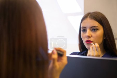 Téléchargez les photos : Portrait d'une belle femme se maquillant près d'un miroir. - en image libre de droit