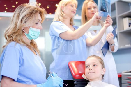 Foto de Paciente asustada con dentista, asistente y enfermera en un consultorio dental - Imagen libre de derechos