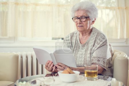 Photo for Grandmother reading book at home. - Royalty Free Image