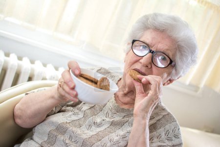 Foto de Retrato de mujer mayor comiendo galletas. - Imagen libre de derechos