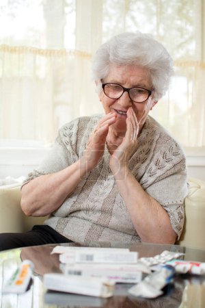 Téléchargez les photos : Femme âgée incroyable regardant beaucoup de médicaments sur la table. - en image libre de droit