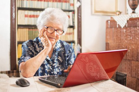 Pensant femme âgée explorant les fonctions de l'ordinateur portable. Technologie, vieillesse et mode de vie concept