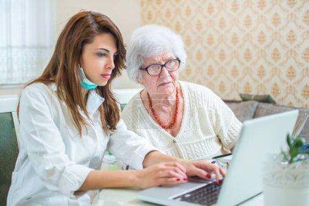 Photo for Nurse and senior patient analyzing medical results on laptop. Home care concept - Royalty Free Image