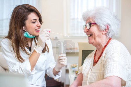 Enfermera usando un hisopo para tomar una muestra de la garganta de las mujeres mayores