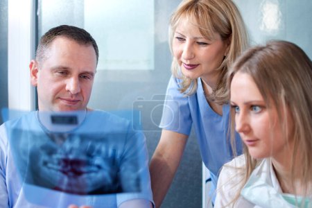 Photo for Dentist team examining patients X-ray image in the office - Royalty Free Image