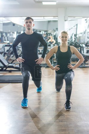 Téléchargez les photos : Couple de fitness sportif faisant des fentes ensemble dans la salle de gym - en image libre de droit