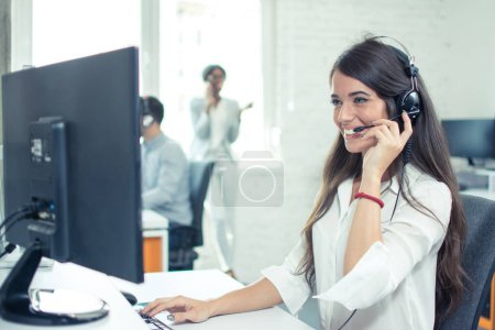 Téléchargez les photos : Travailleur du centre d'appels avec casque de travail sur ordinateur. Opérateur de soutien à la clientèle souriant au travail. - en image libre de droit