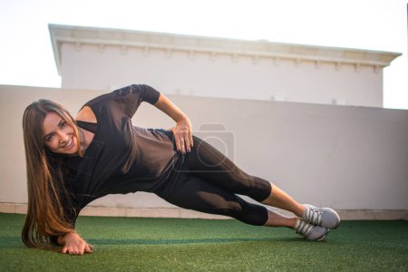 Téléchargez les photos : Jeune femme sportive faisant planche latérale à l'extérieur. - en image libre de droit