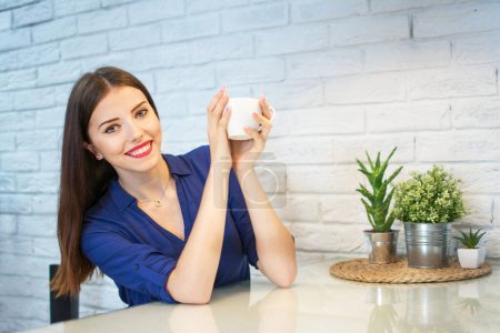 Photo for Happy young woman holding a cup of coffee at home. - Royalty Free Image